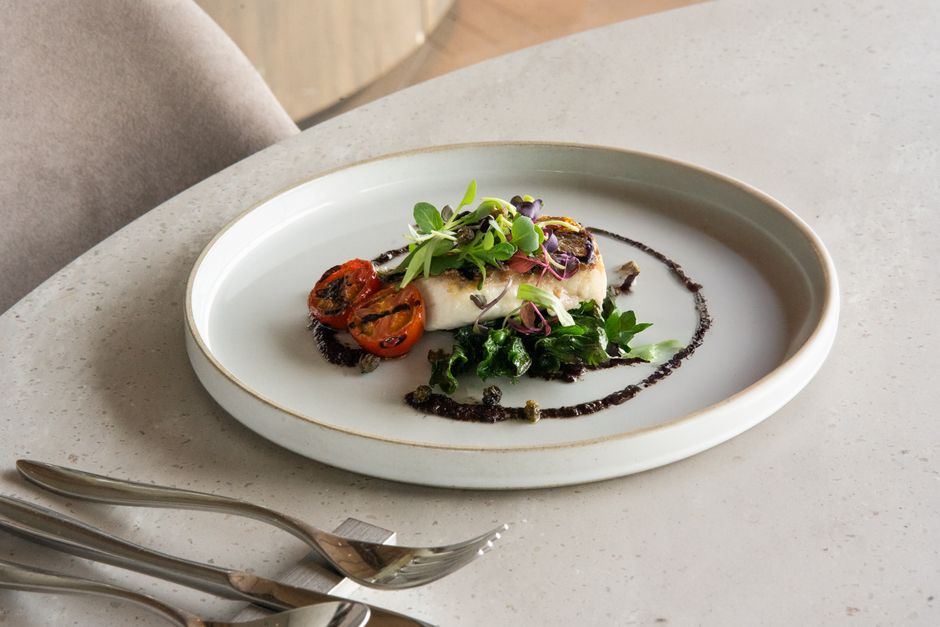 Plato gourmet delicado con tomates asados y verdes en plato blanco
