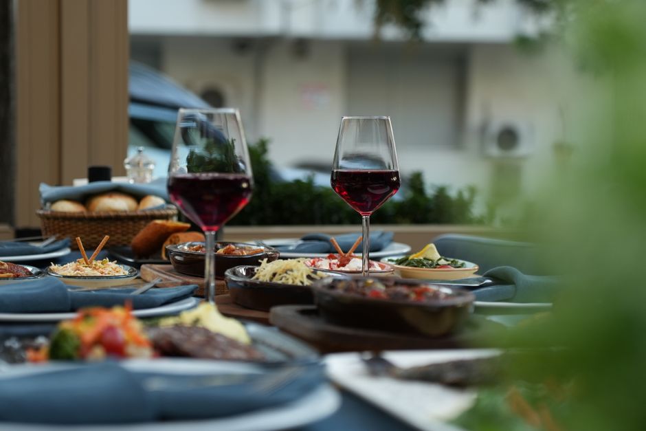 Lujosa mesa exterior con vino tinto y platillos gourmet para una cena sofisticada